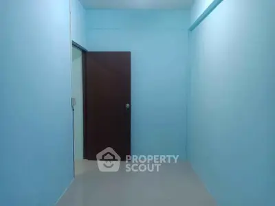 Minimalist blue room with brown door, ideal for storage or small office space.