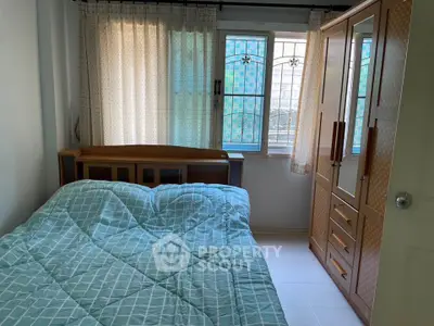 Cozy bedroom with wooden furniture and natural light through window.