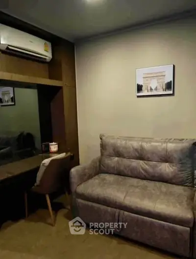 Cozy living room with plush sofa and wall-mounted air conditioner, perfect for relaxation.