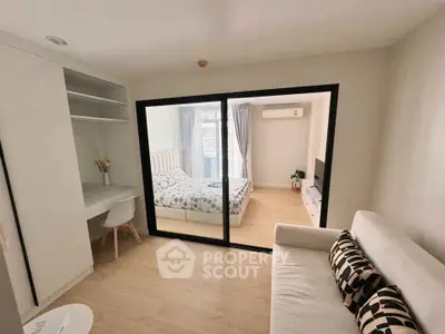 Modern studio apartment with cozy living area and stylish bedroom separated by glass doors.