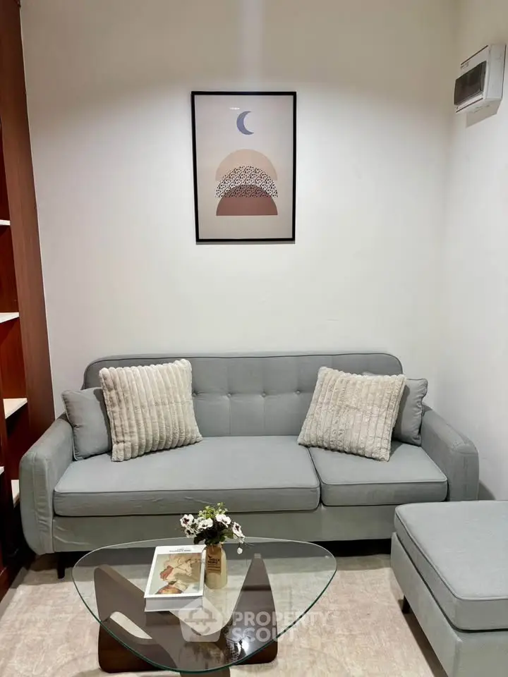 Cozy living room with modern gray sofa and stylish glass coffee table, perfect for relaxation.