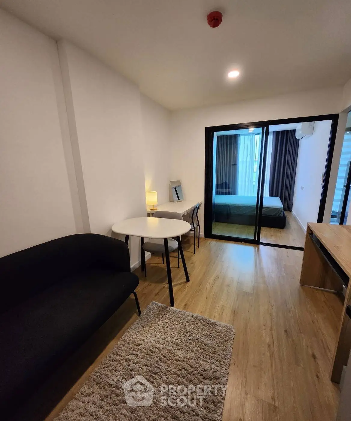 Modern apartment with cozy living area and bedroom separated by glass doors.