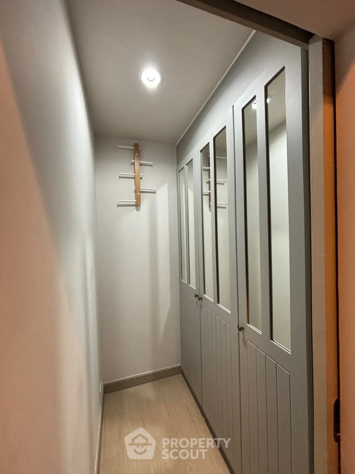 Spacious walk-in closet with mirrored doors and modern lighting