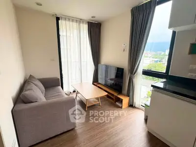 Modern living room with cozy sofa, flat-screen TV, and large windows offering scenic views.