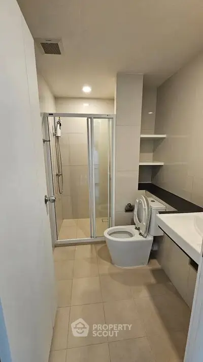 Modern bathroom with glass shower and sleek fixtures in a contemporary apartment.