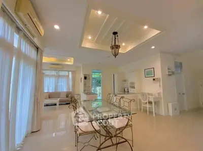 Spacious open-plan living and dining area with elegant glass table and stylish lighting.