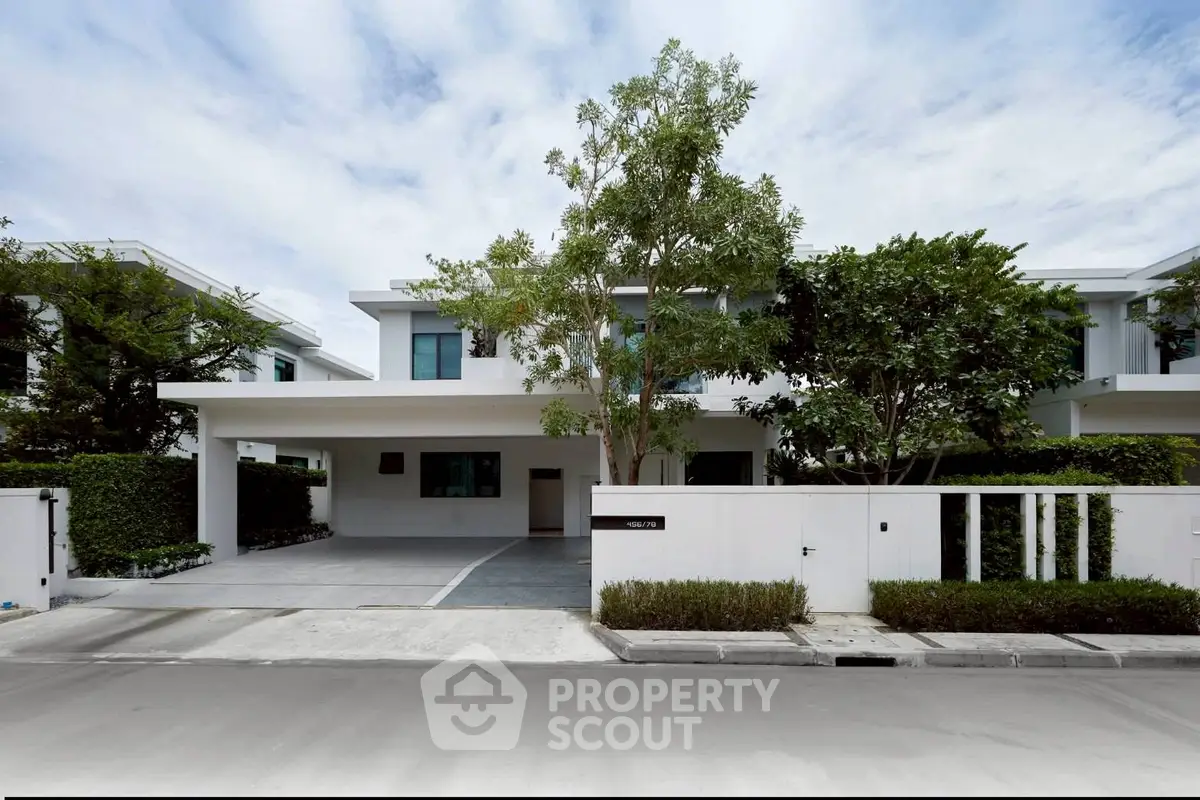Modern two-story house with sleek design and lush greenery in a serene neighborhood.