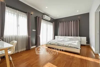 Spacious modern bedroom with wooden flooring and ample natural light