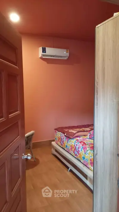 Cozy bedroom with air conditioning and colorful bedding, perfect for a comfortable living experience.