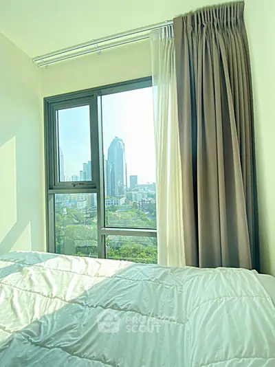 Bright bedroom with city view through large window and elegant curtains.