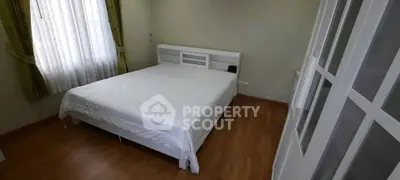 Spacious bedroom with natural light and elegant wooden flooring.