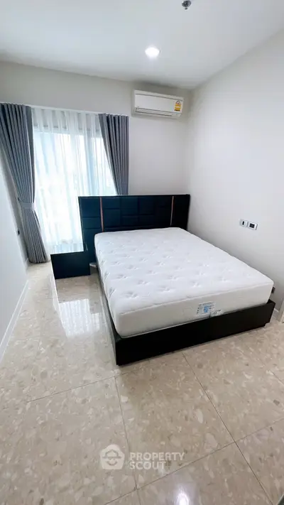 Modern bedroom with sleek design and natural light, featuring a comfortable bed and air conditioning.