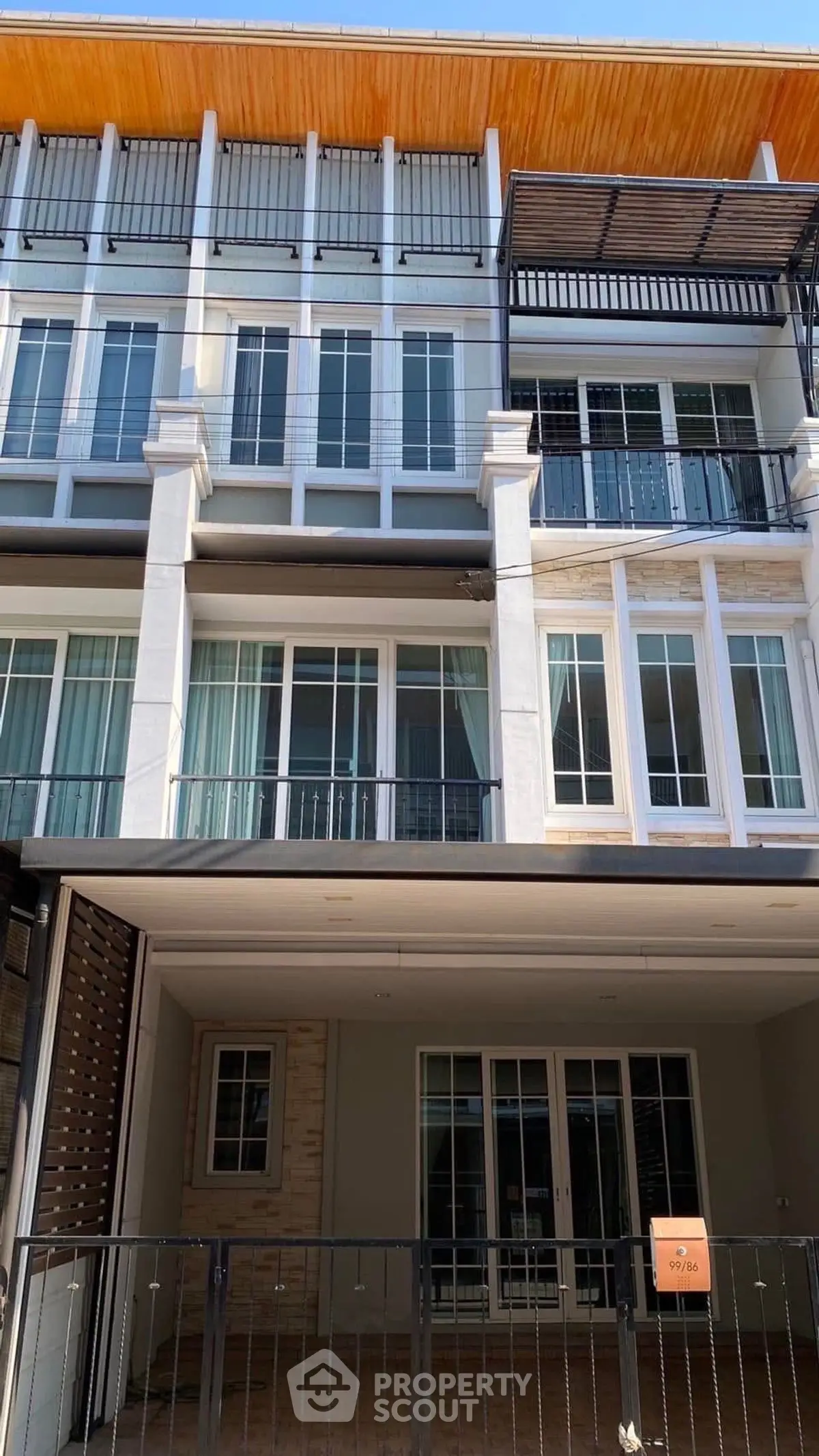 Modern multi-story townhouse with large windows and balconies, ideal for urban living.