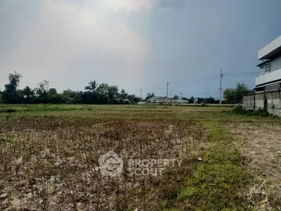 Expansive vacant land with potential for development, surrounded by greenery and clear skies.