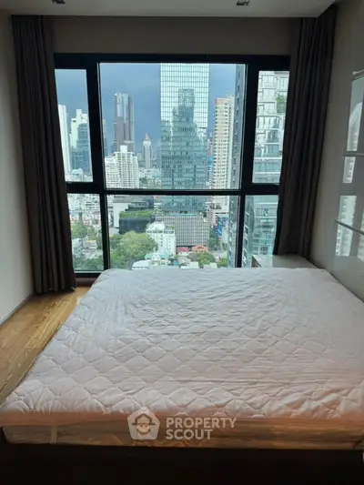 Modern bedroom with stunning city view from large window in high-rise apartment.