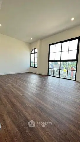 Spacious living room with large windows and wooden flooring, offering abundant natural light and scenic views.
