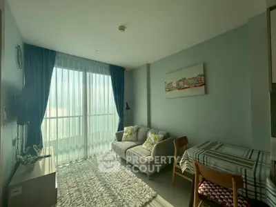 Bright living room with cozy sofa and dining area, featuring large window and stylish decor.