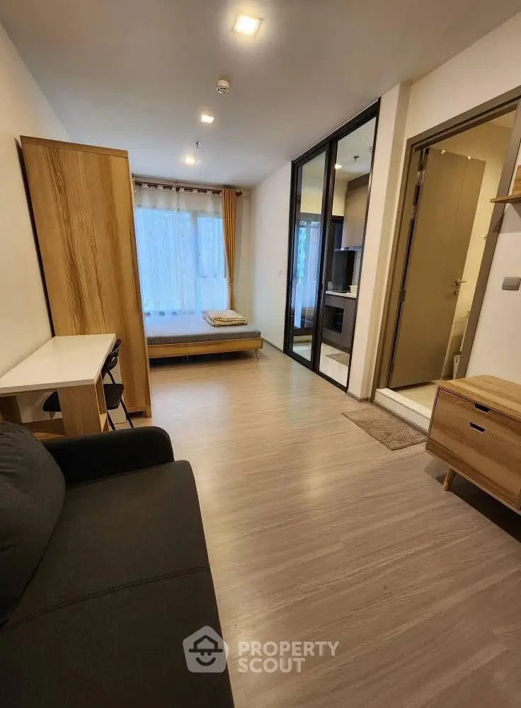Modern studio apartment with sleek wooden flooring and stylish furniture, offering a cozy and functional living space.