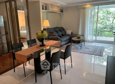 Modern living room with elegant dining area and large windows overlooking greenery.