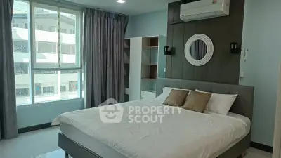 Spacious bedroom with modern decor and large window offering natural light.