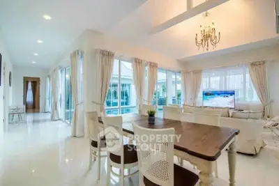Spacious and elegant living room with large windows and chandelier, perfect for entertaining.