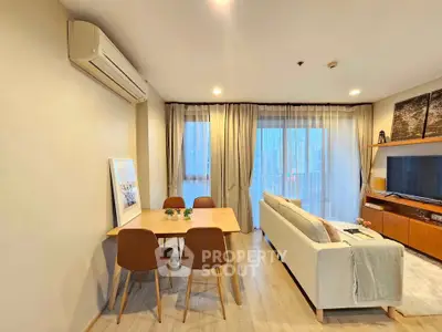 Modern living room with dining area, featuring sleek furniture and large windows for natural light.
