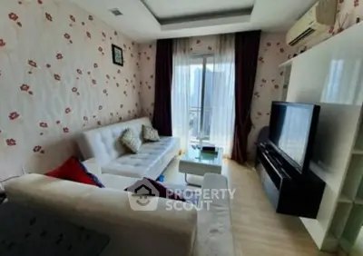 Charming living room with floral wallpaper, cozy sofas, and large TV, perfect for relaxation.