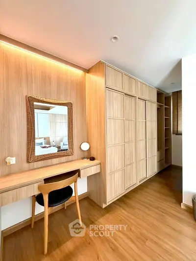Elegant study area with wooden desk and mirror, featuring built-in storage and warm lighting.