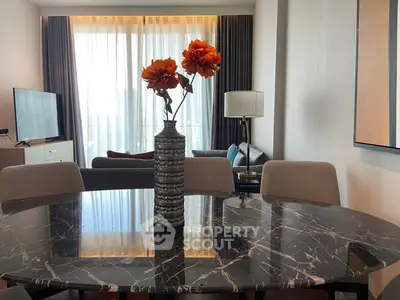 Elegant living room with marble table and modern decor, featuring large windows and stylish furniture.