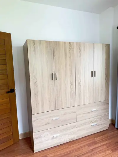 Spacious wooden wardrobe in a modern bedroom with wooden flooring.