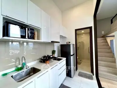 Modern kitchen with sleek white cabinets and stainless steel appliances in a stylish apartment.