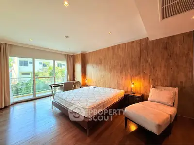 Spacious bedroom with wooden flooring and large windows offering natural light and a serene view.