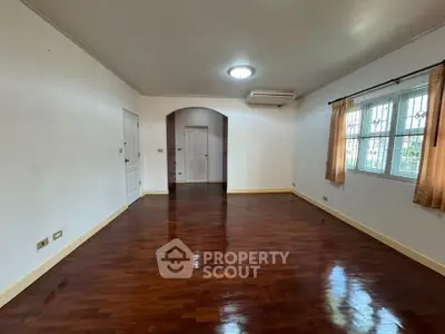 Spacious living room with polished wooden floors and large windows.