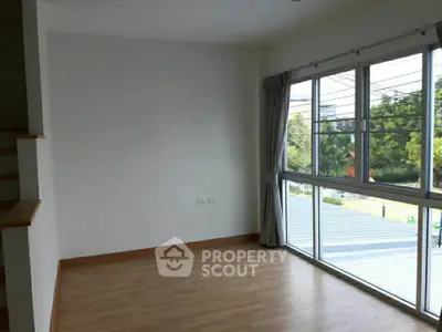 Bright empty room with large windows and wooden flooring, ideal for customization.