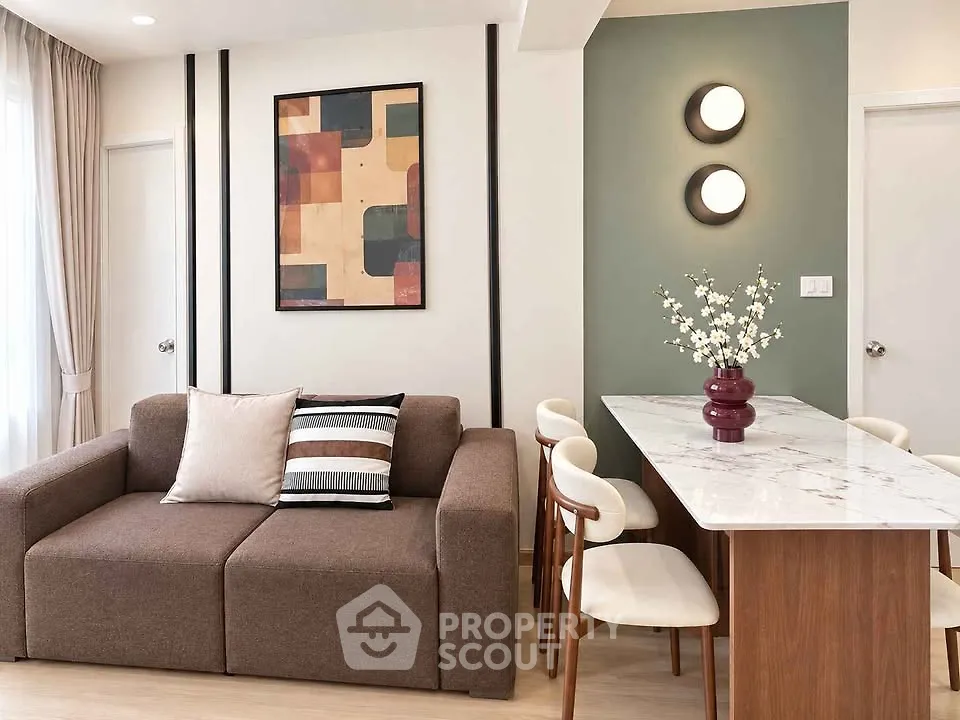 Modern living room with stylish decor and dining area, featuring a cozy sofa and elegant lighting.