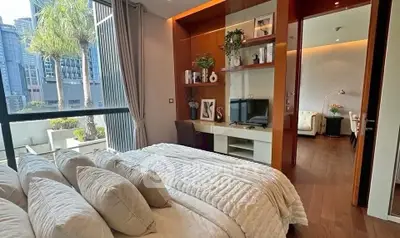Luxurious bedroom with city view and modern decor, featuring a cozy workspace and elegant furnishings.