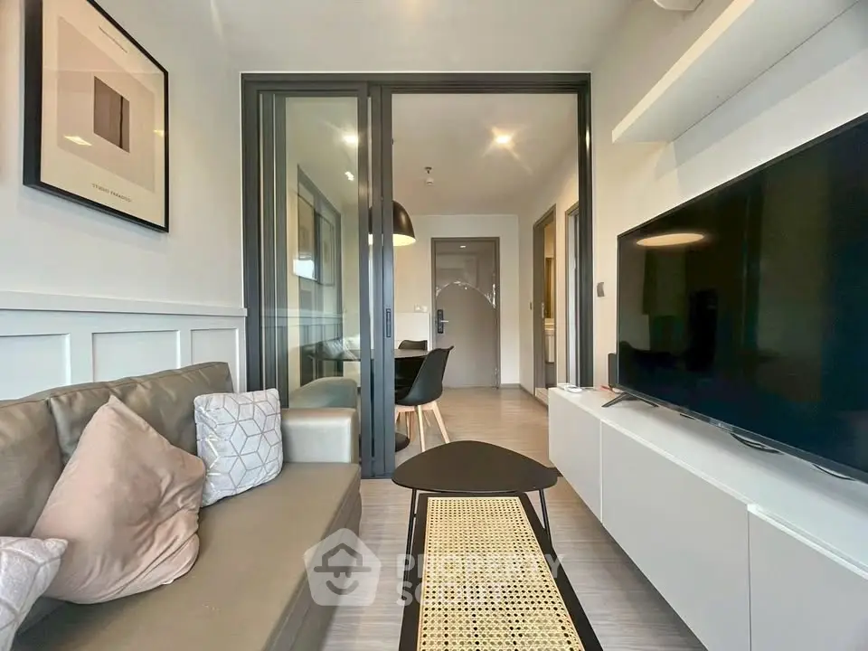 Modern living room with sleek furniture and large TV in a stylish apartment.