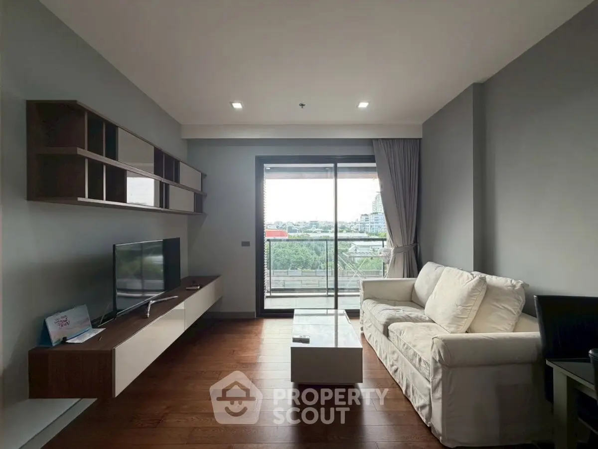 Modern living room with balcony view, featuring sleek furniture and natural light.