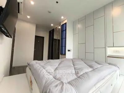 Modern bedroom with sleek design, built-in wardrobe, and wall-mounted TV in a stylish apartment.