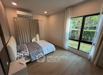 Spacious bedroom with large window and garden view, featuring modern decor and natural light.