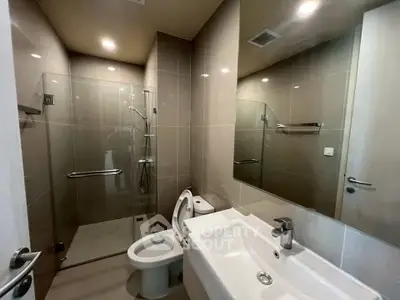 Modern bathroom with sleek fixtures and glass shower enclosure in a contemporary apartment.
