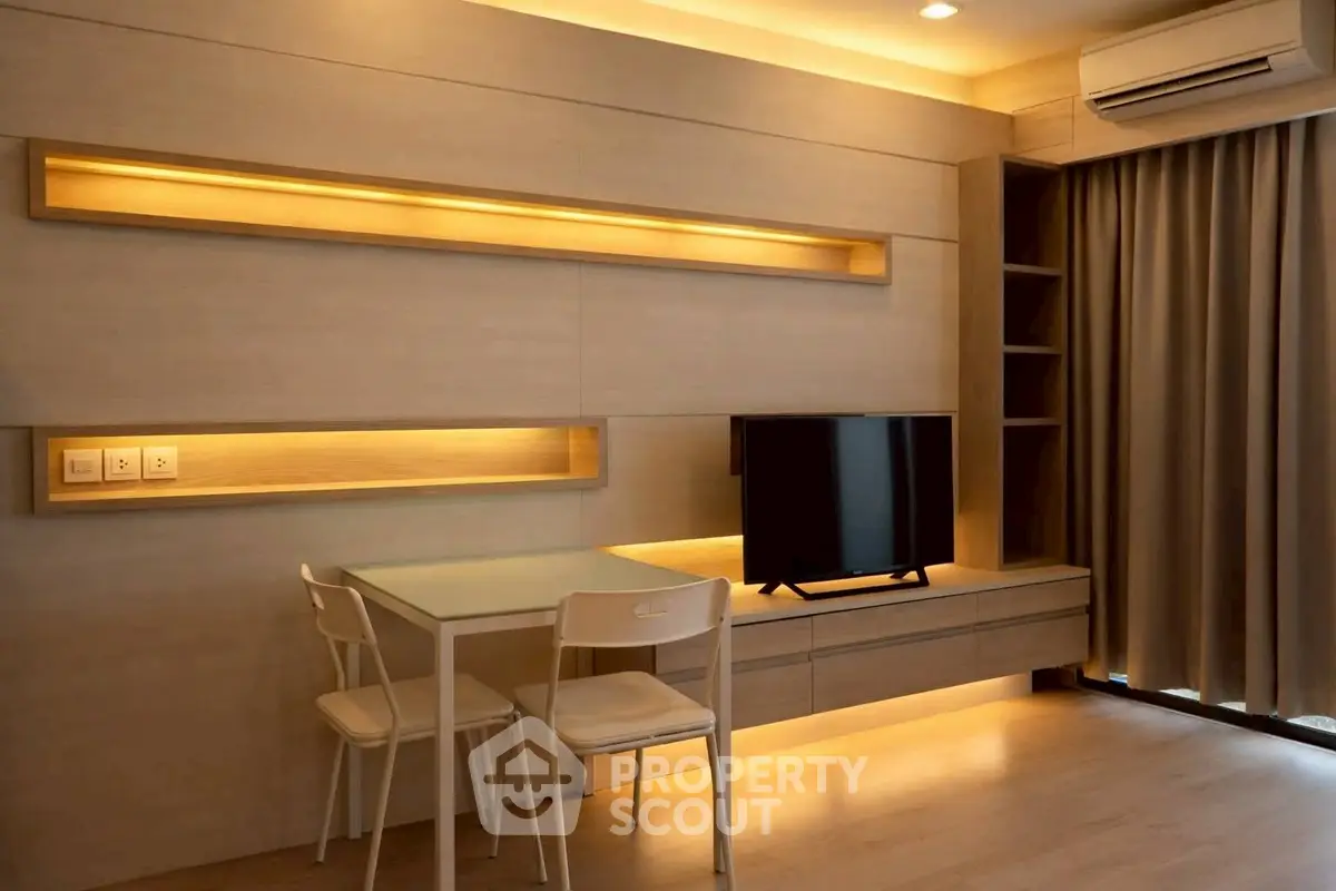 Modern living room with sleek furniture and ambient lighting, featuring a mounted TV and stylish dining area.