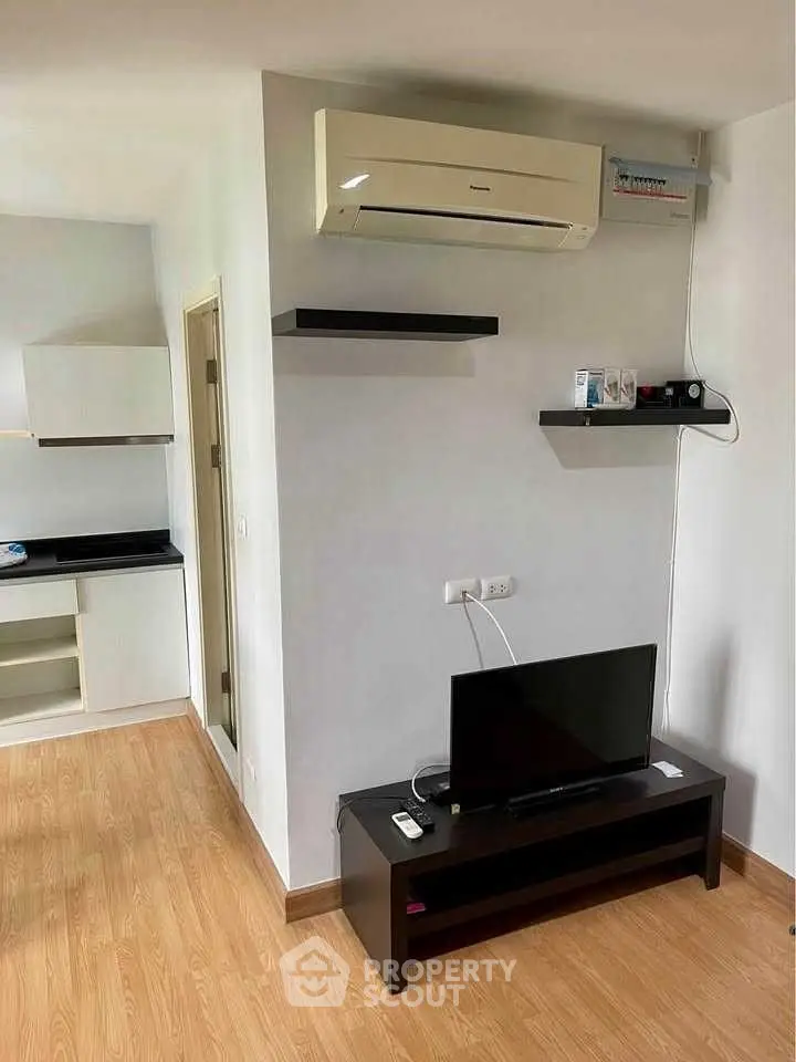 Modern living room with sleek TV stand and wall-mounted air conditioner in a cozy apartment.