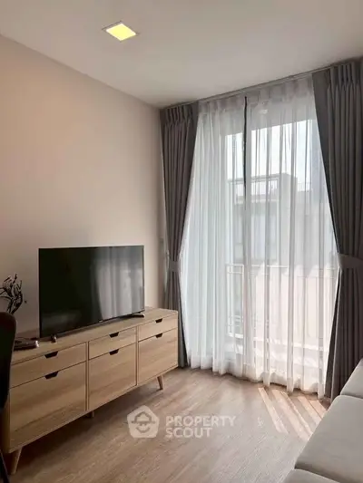 Modern living room with TV and large window with sheer curtains