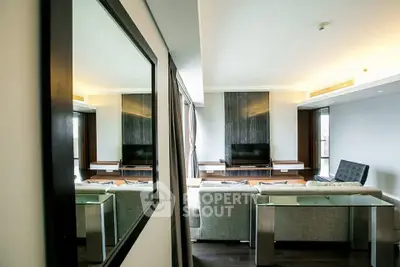 Modern living room with sleek furniture and large mirror reflecting elegant design.