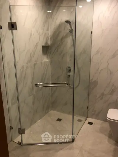 Modern bathroom with glass shower enclosure and marble walls