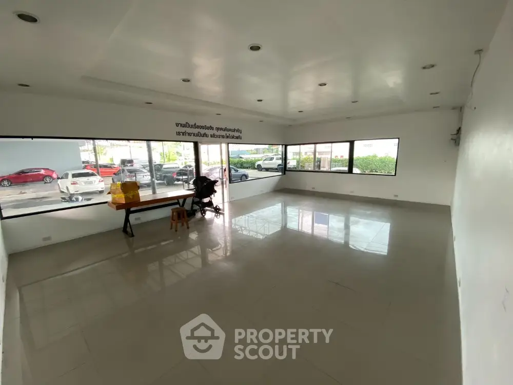 Spacious empty room with large windows and tiled flooring, ideal for versatile use.