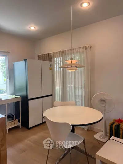 Charming kitchen with modern fridge and stylish dining area, perfect for cozy meals.