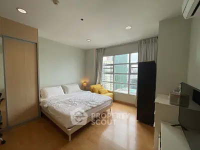 Spacious bedroom with city view, modern furnishings, and natural light.