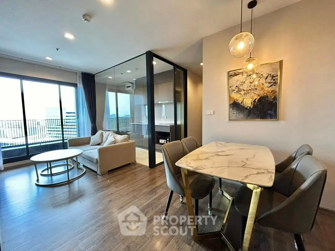 Modern living room with open layout and stylish dining area, featuring large windows and elegant decor.